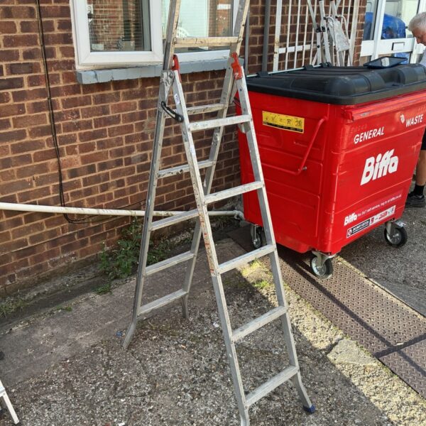Vintage metal step ladder leaning against a Biffa bin.