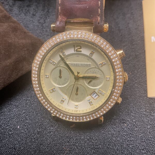 Gold Michael Kors wristwatch with crystal bezel and leather strap.