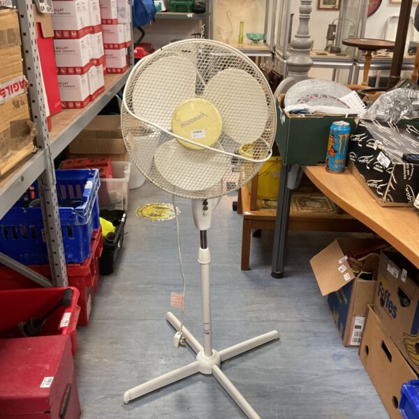 White vintage Micromark pedestal fan in a cluttered room.