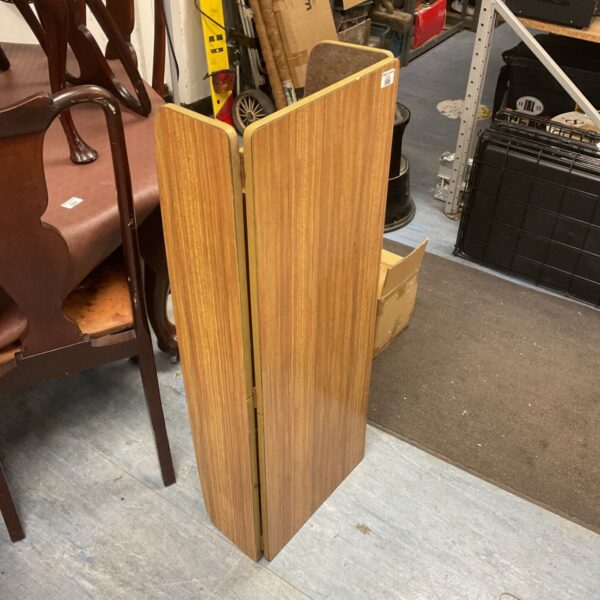 Vintage mid-century teak gateleg table in a cluttered room.