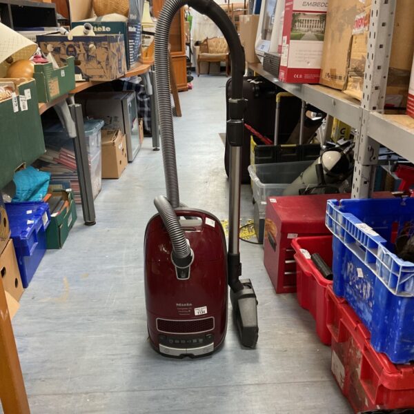 Miele C3 Cat & Dog Powerline vacuum cleaner in a cluttered room.
