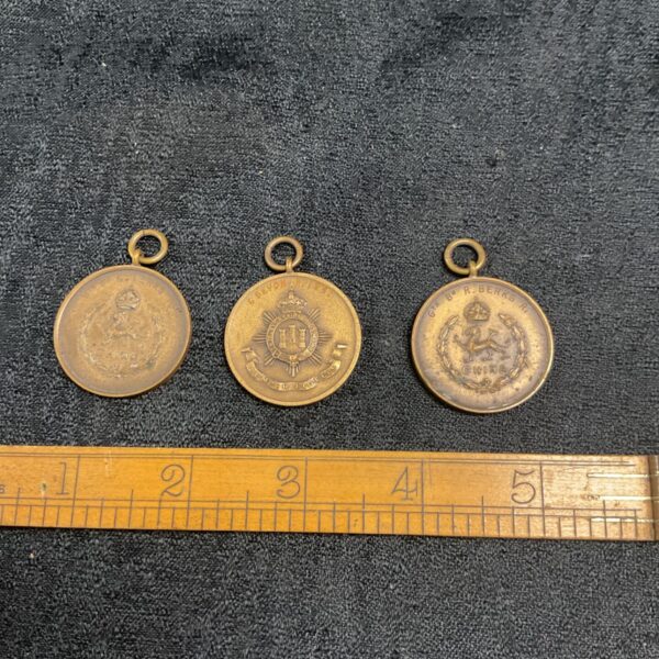 Group of three vintage military bronze medals with loops.