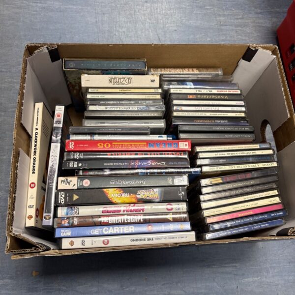 Mixed lot of CDs and DVDs in a cardboard box.