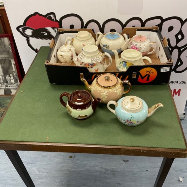 Mixed collection of vintage ceramic tea pots on display.