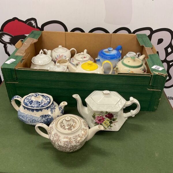 Mixed lot of vintage ceramic tea pots on display.
