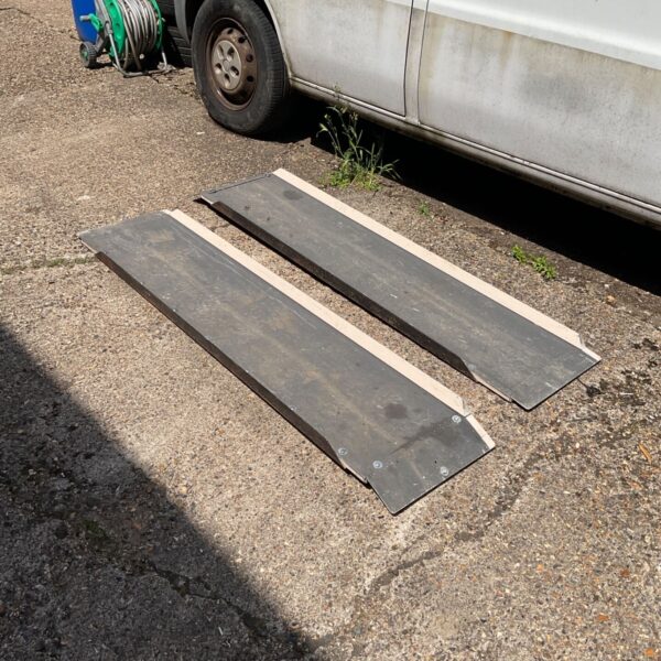 Wooden mobility access ramps lying on a paved surface.