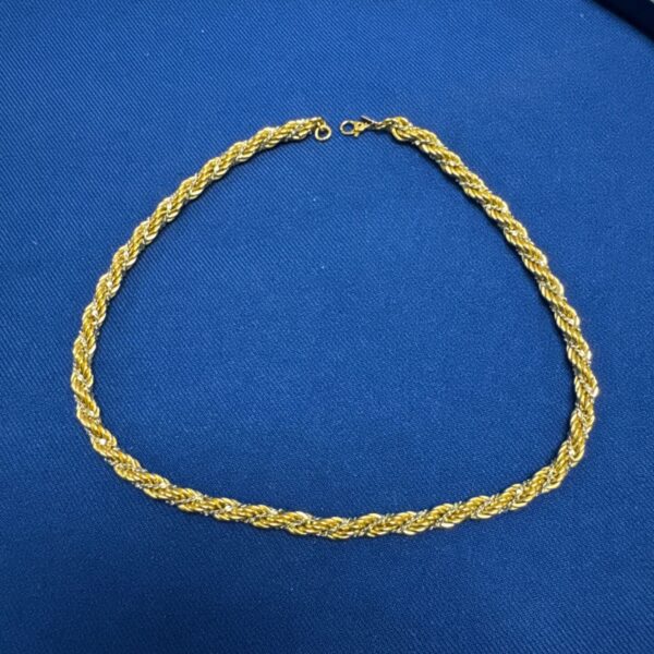 Gold and silver Monet twist necklace displayed on a blue background.