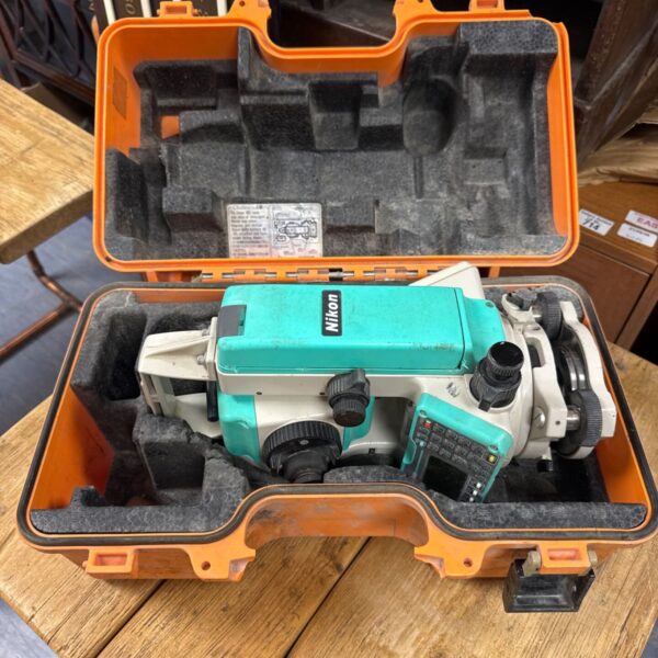 Open case showing Nikon DTM-332 total station and accessories.