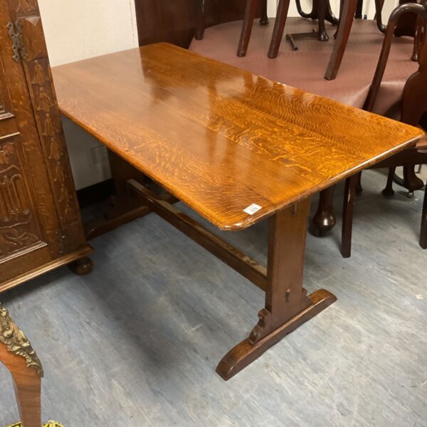 Vintage oak refectory table with trestle base in a showroom.