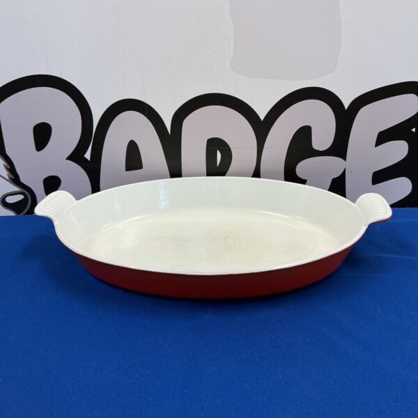 Vintage orange enamel cast iron casserole dish for cooking.