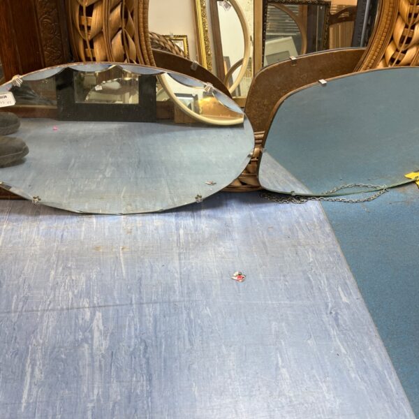 Pair of ornate oval hanging mirrors with gilded frames.