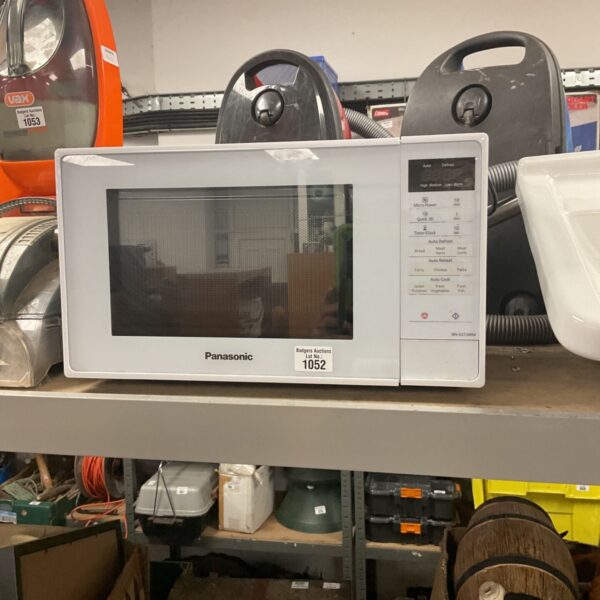 Vintage Panasonic microwave in a cluttered space.