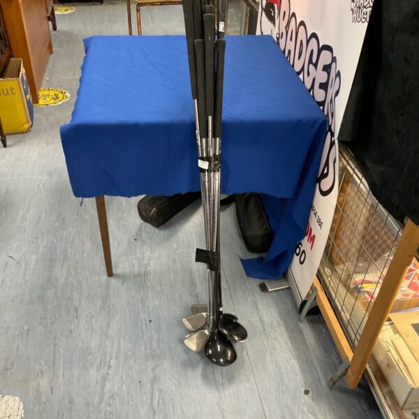 Paradigm golf clubs displayed on a blue table, showing wear.