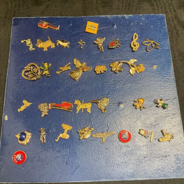 Assorted vintage enamel pin badges on a card.