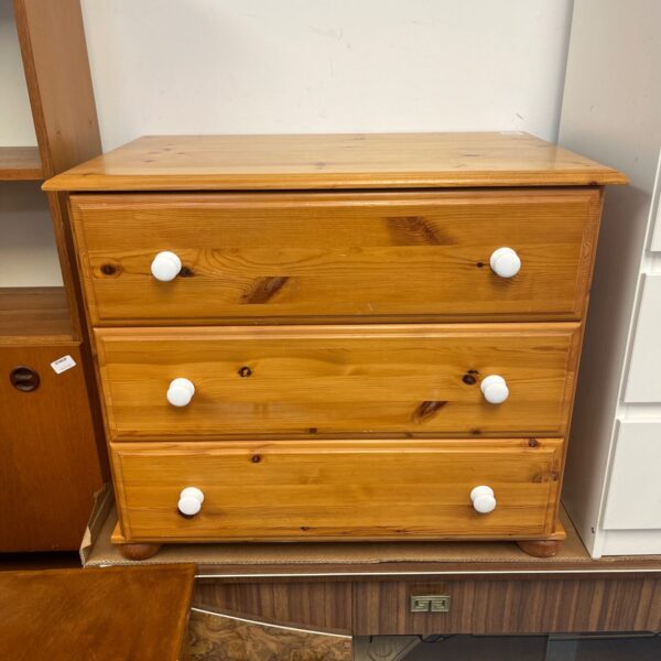 Vintage pine chest of drawers with white knobs and bun feet.