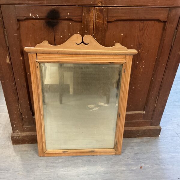 Antique pine framed wall mirror with a curved top.