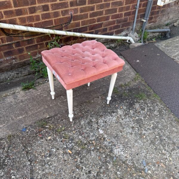 Pink velvet stool with button detailing and painted legs.