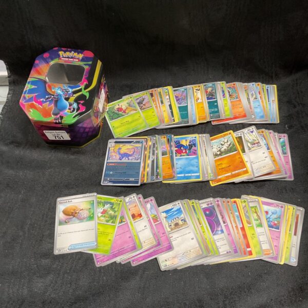 Pokemon card tin 751 with assorted trading cards.