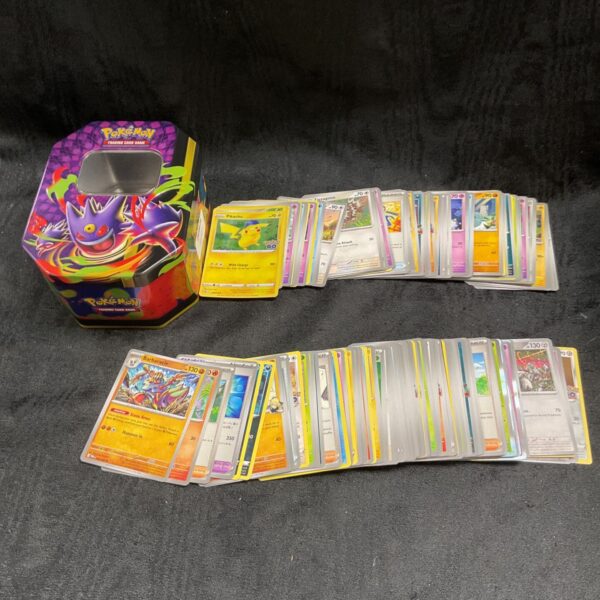 Colourful Pokemon card tin with assorted trading cards inside.