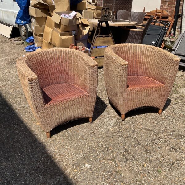 Pair of vintage rattan garden chairs in a garden setting.