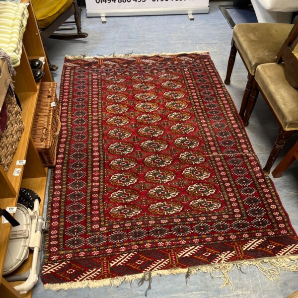 Red Bokhara rug with geometric patterns, handmade wool textile.