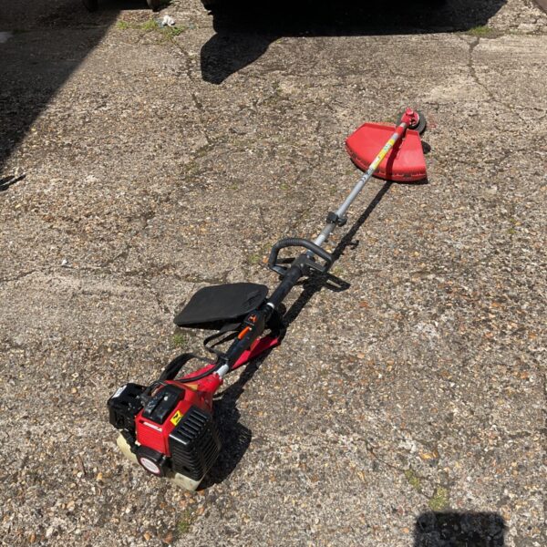 Red petrol grass strimmer for garden maintenance and lawn edging.