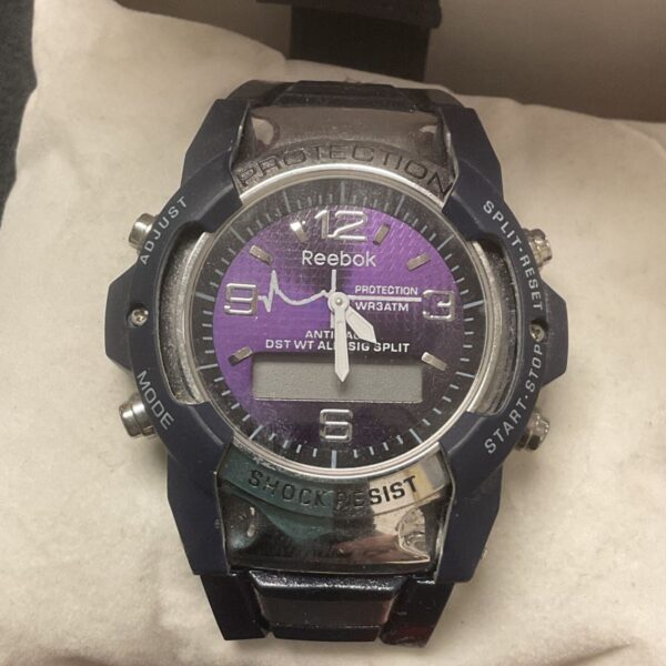 Reebok wristwatch with a purple face and black strap.