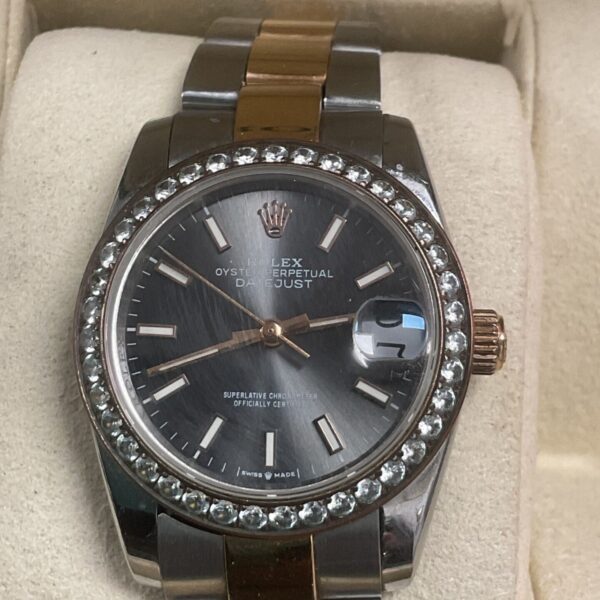 Close-up of Rolex Datejust watch with diamond bezel and grey dial.