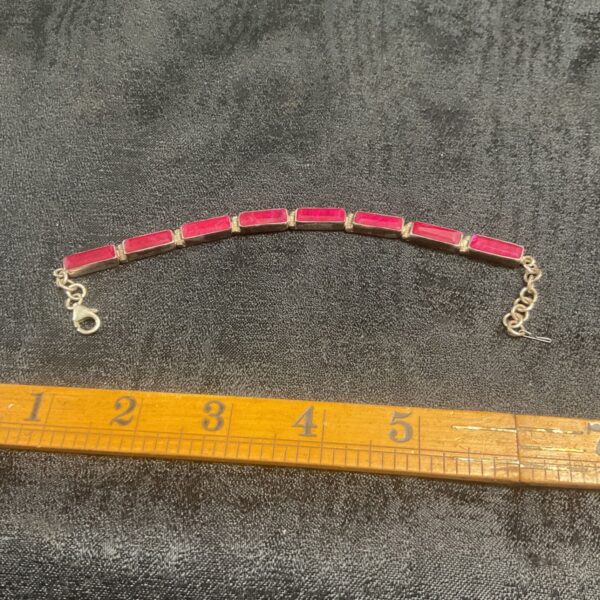 Silver ruby tennis bracelet with rectangular red stones.
