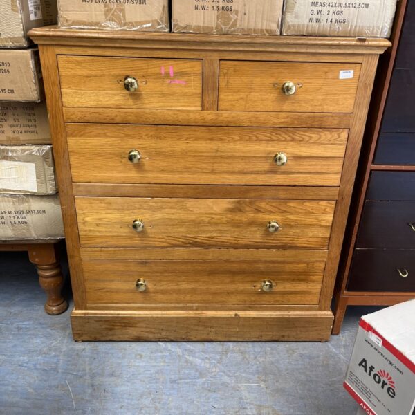 Rustic pine chest of drawers with brass knobs for bedroom storage.