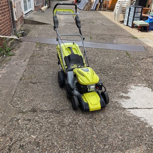 Used Ryobi petrol lawnmower in a garden setting.