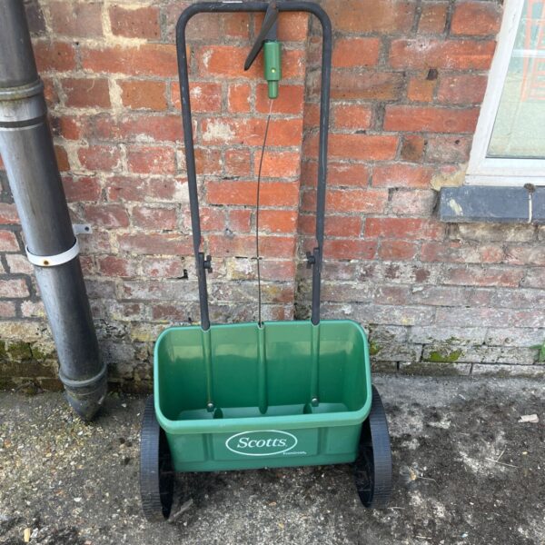 Green Scotts drop spreader for even lawn fertilizer application.