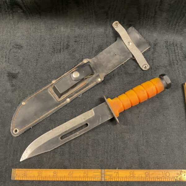 Large sheath knife with orange handle and included oil stone.