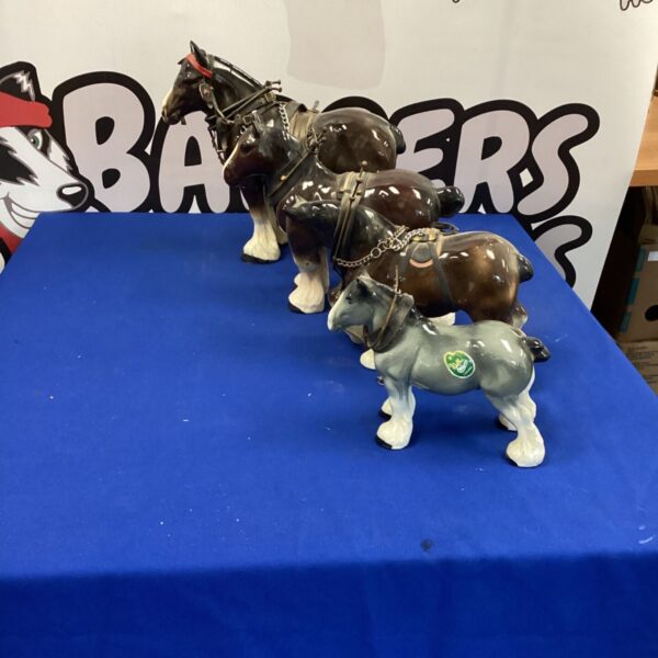 Set of four vintage china Shire horse ornaments displayed.