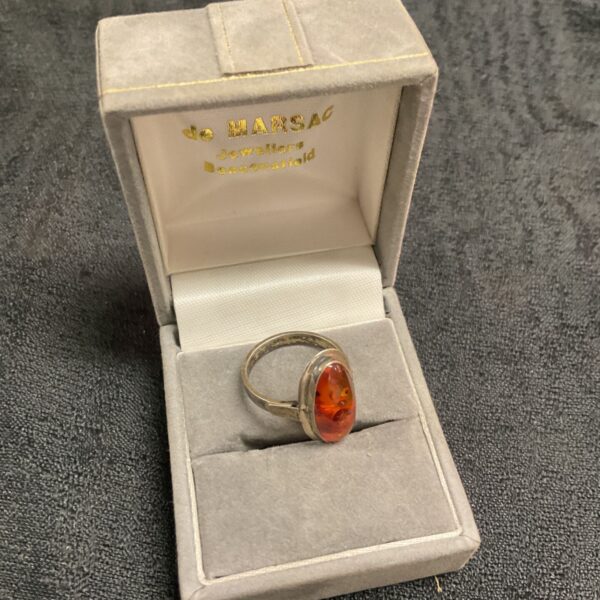 Close-up of a vintage silver ring with a large amber gemstone.