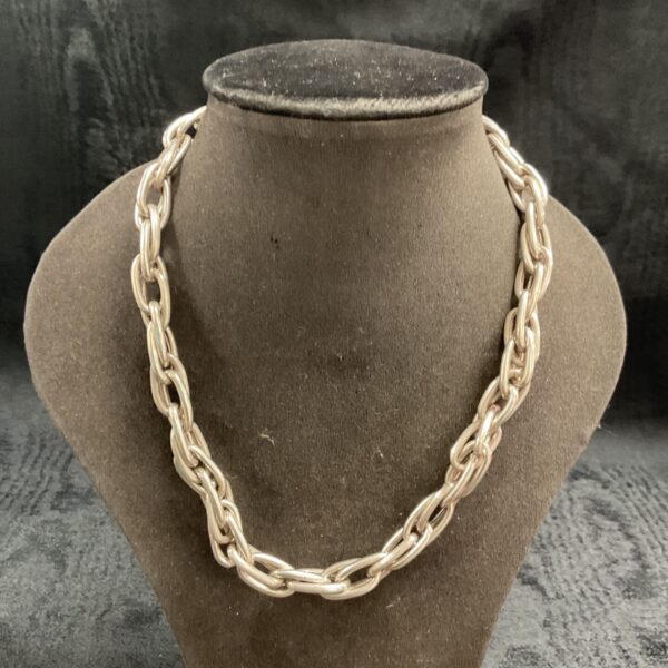 Close-up of a heavy silver chain necklace with bold links.