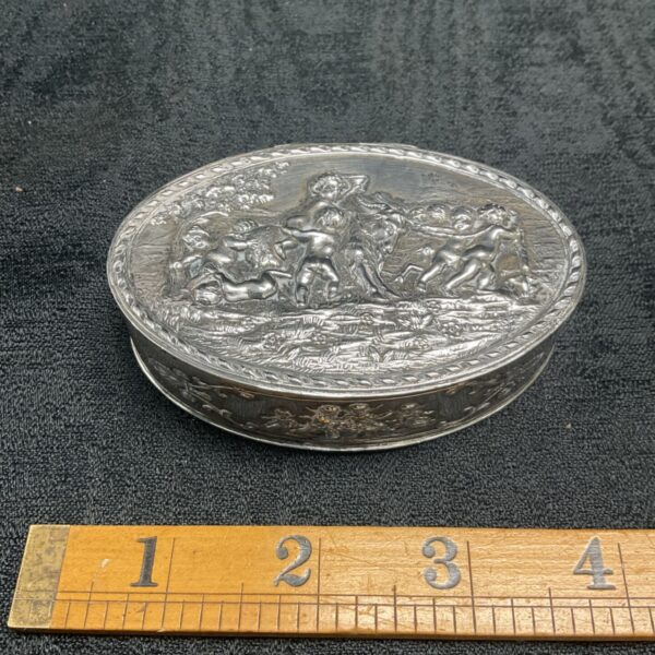 Antique silver trinket box with cherub repousse on the lid.