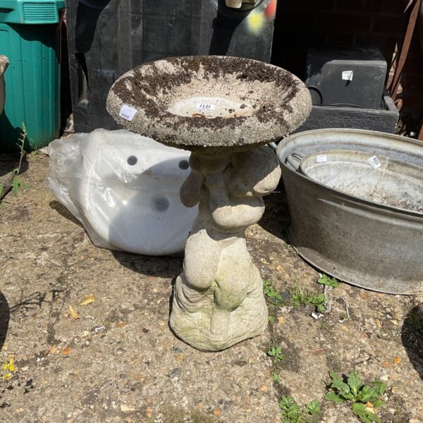 Stone bird bath in a garden setting, providing a water source for birds.