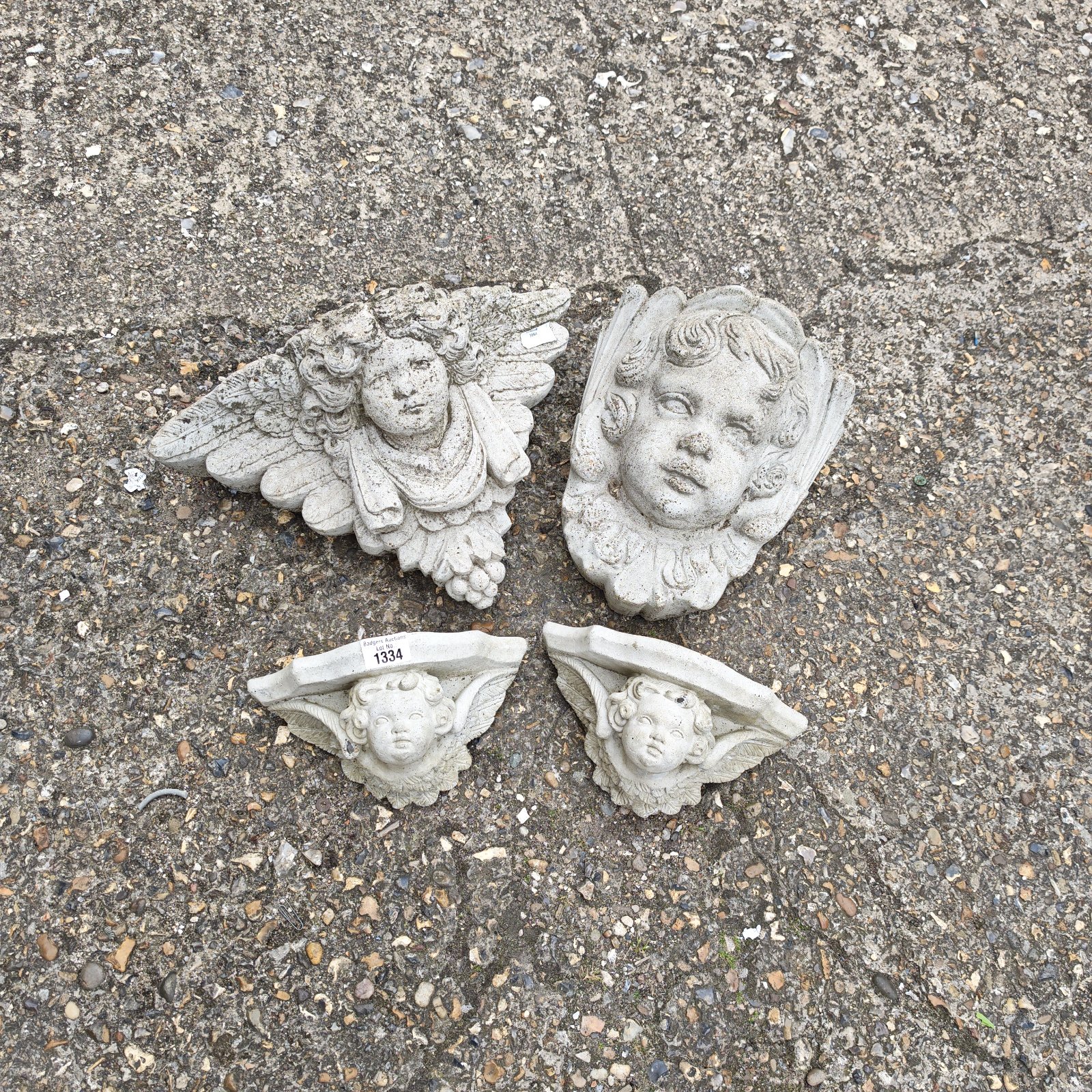 Antique stone cherub scones with detailed angel faces for shelf support.