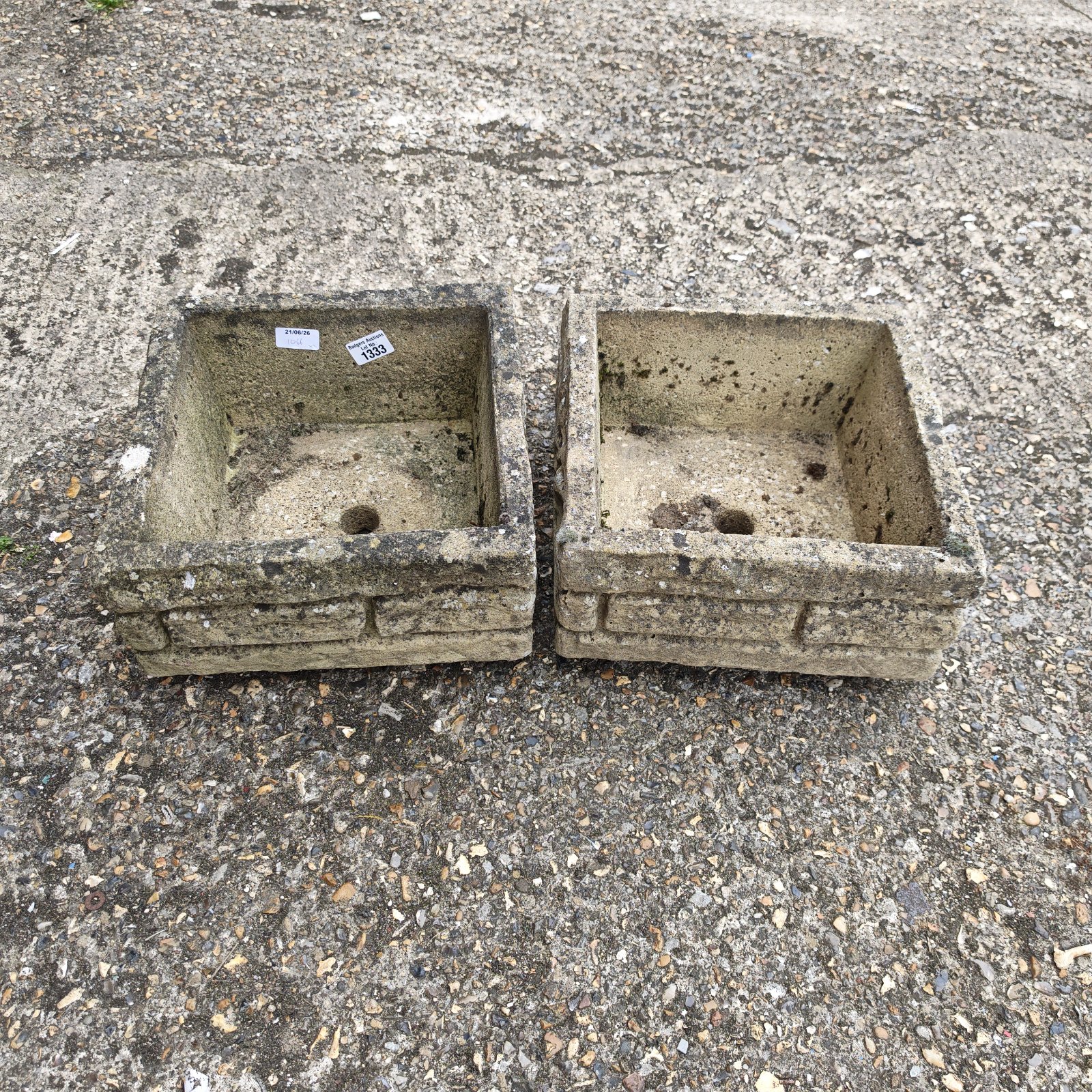 Pair of weathered stone garden planters for outdoor use.