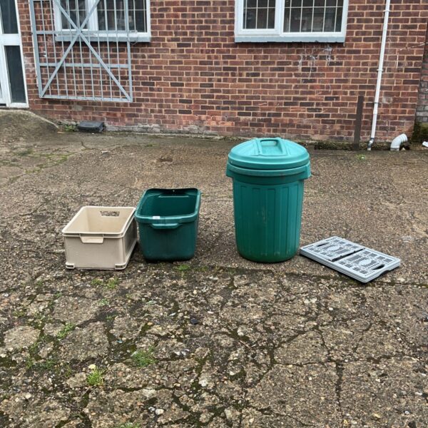 Collection of plastic storage containers and a green garden bin.