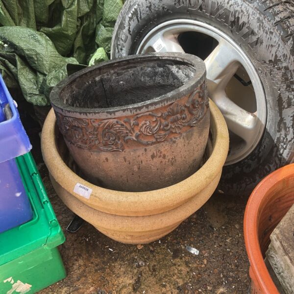 Embossed terracotta flower pot in a garden setting.
