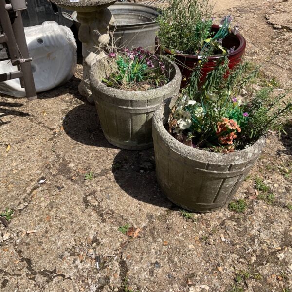 Two terracotta garden planters with colourful plants in a garden setting.