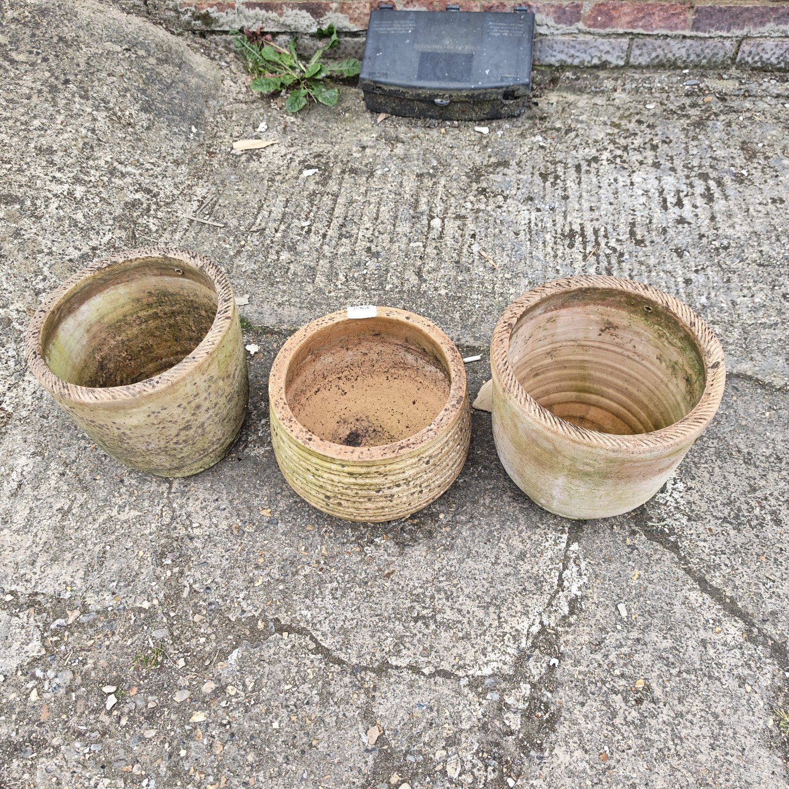Three weathered terracotta garden plant pots with ribbed texture.