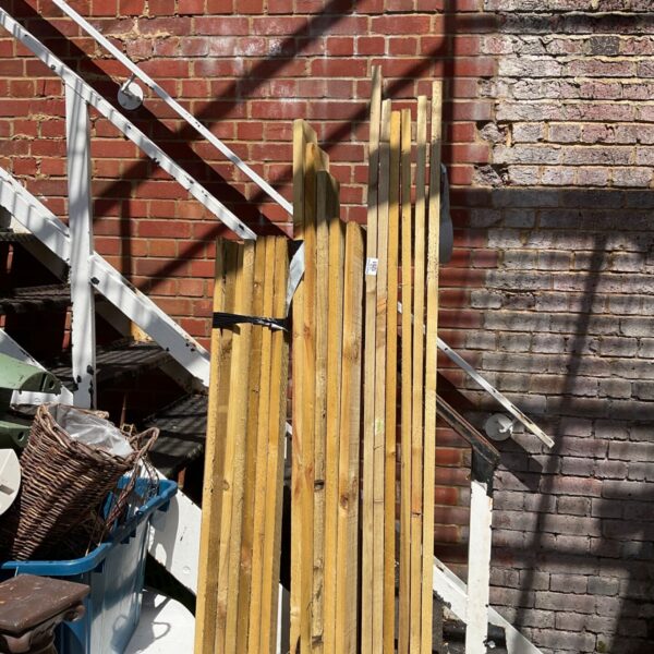 Three bundles of 6ft timber leaning against a brick wall.