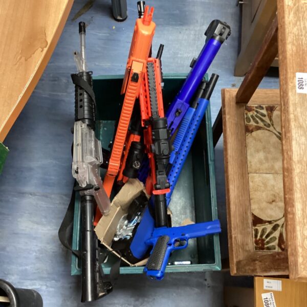 Assorted plastic toy guns in orange, blue, and grey.