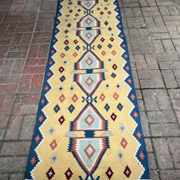 Vintage Turkish Kilim runner with yellow background and geometric patterns.