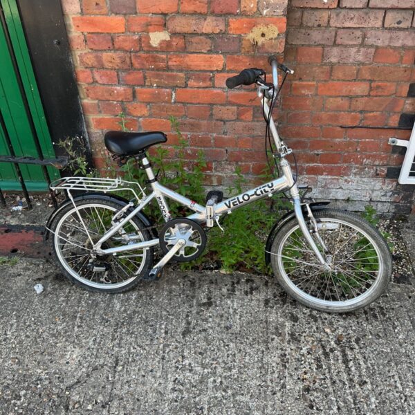 Vintage Velo-city Bronx folding bicycle in a garden setting.