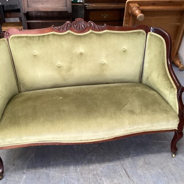 Green upholstered Victorian settee with carved wooden frame.