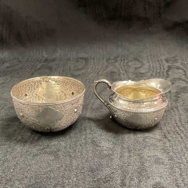 Victorian silver cream jug and sugar bowl with floral embossing.